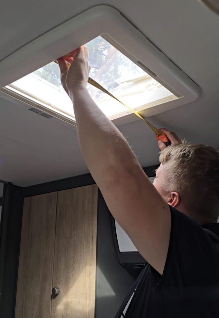 Mies asentaa asuntovaunun kattoluukun kohdalle ilmastointilaitetta.