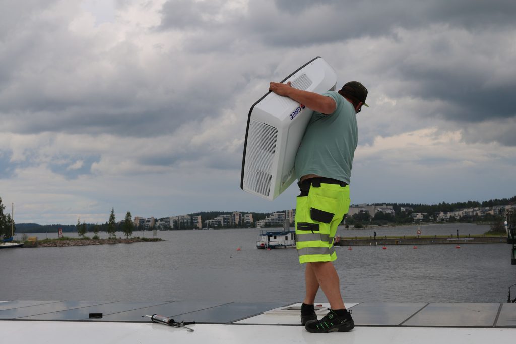 Mies asentaa Gree Shark- ilmastointilaitetta asuntolautan katolle.